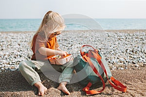 Kid with lunch box eating healthy food on beach travel lifestyle summer vacations child with lunchbox