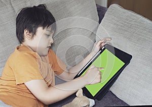 Kid lying on sofa playing game on tablet, Child boy relaxing at home drawing or wring on digital pad, Children avtivity for new