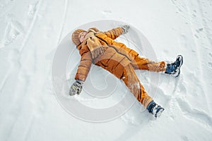 Kid making a snow angel in winter park