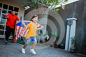 Kid with malaysia flag running and playing chase with daddy