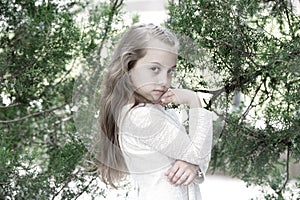 Kid model with fresh face skin in summer nature. Girl in fashion dress pose at green tree. Little child with long blond