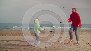 Kid and mom playing beach tennis near the sea