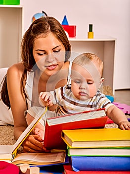 Kid and mother baby boy lying on floor and read book.