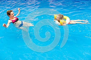 Kid and mother in water at sea beach. Little girl floating in pool with inflatable ring. Child at swimming lesson with mom