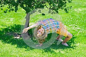 Kid on nature. Kid boy having fun at park outdoor. Happy child standing upside down on green grass. Healthy lifestyles