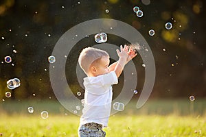 Kid in nature reaching soap bubbles