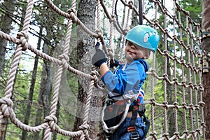 Kid overcoming mesh obstacle in forest adventure park