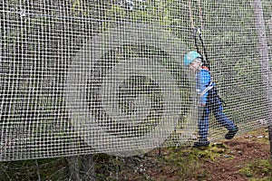 Kid overcoming mesh obstacle in rope adventure park