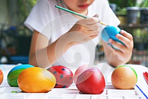 Kid painting easter egg with vibrant color