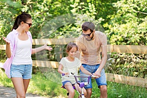 Kid with patents learning to ride bicycle in park