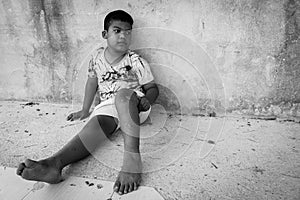 Kid pauper sitting against the concrete wall