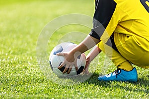 Kid picks up the ball from the playing field. Child holding a soccer ball in hands