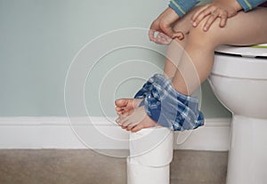 Kid pinching fingers to help with stomach ache, Child boy having with bad tummy problem and diarrhea,Low view of  legs hanging