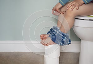 Kid pinching fingers to help with stomach ache, Child boy having with bad tummy problem and diarrhea,Low view of  legs hanging photo