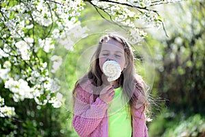 Kid in pink sweater eats lollipop. Girl with dreamy face