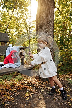 Kid play with dog on big wooden chai in the garden