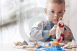 Kid play with lifebuoy and starfish. Child play with sea shells and boats. Summer vacation and travel concept.