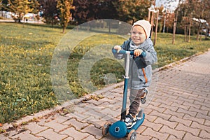 Kid play outdoors with kick scooter. Active leisure and outdoor sport for child. Happiness and childhood concept. Child