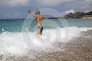 kid play with splahes waves of the sea