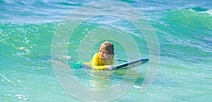Kid play in summer sea. Kids outdoor water sport, swimming activity in surf camp. Summer vacation with child. Surfer
