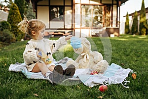 Kid play with teddy bear in the garden