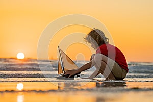 Kid playing on the beach. Child play on the sea with toy ship boat. Little child having a happy moment play with toy