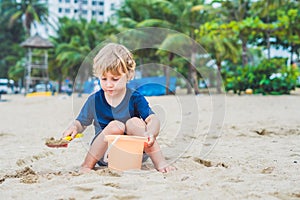 Kid playing on the beach with the children`s shovel and a bucket