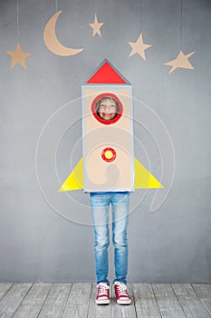 Kid playing with cardboard rocket at home