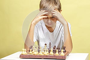 Kid playing chess. Boy looking at chess board and thinking about his strategy.