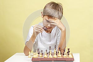 Kid playing chess. Boy looking at chess board and thinking about his strategy.