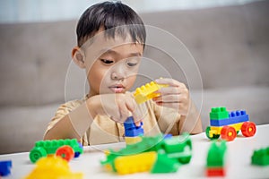 The kid playing with colorful toy blocks. Little boy building the car of block toys. Educational and creative toys and games for