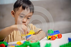 The kid playing with colorful toy blocks. Little boy building the car of block toys. Educational and creative toys and games for