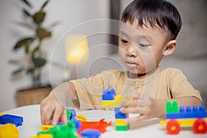 The kid playing with colorful toy blocks. Little boy building the car of block toys. Educational and creative toys and games for