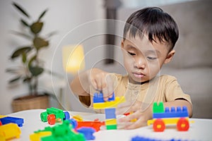 The kid playing with colorful toy blocks. Little boy building the car of block toys. Educational and creative toys and games for