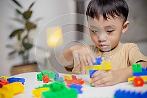 The kid playing with colorful toy blocks. Little boy building the car of block toys. Educational and creative toys and games for