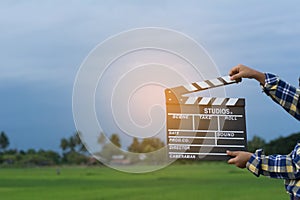 Kid playing film clapper board against summer sky background. Film director concept.