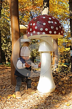 Kid playing by giant wooden mushrooms