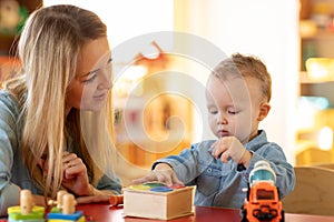 Kid playing logical toys with educator or mother in the classroom in nursery or preschool