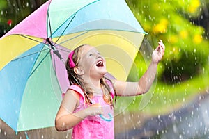 Kid with umbrella playing in summer rain.