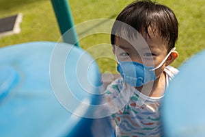 kid playing at the park playground with medical face mask during day time