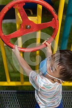 kid playing at the park playground with medical face mask during day time