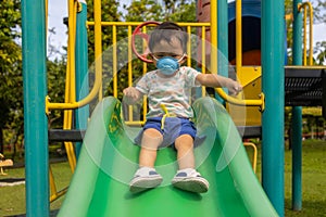 kid playing at the park playground with medical face mask during day time