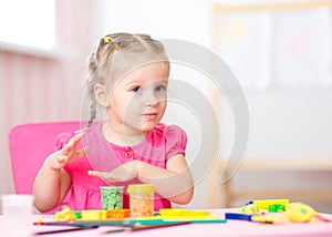 Kid playing with play clay at home or playschool photo