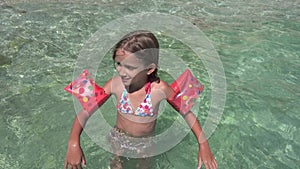 Kid Playing in Sea Water on Beach, Child Plays on Seashore, Blonde Little Girl with Swimming Life Buoy Enjoying Waves on Coastline