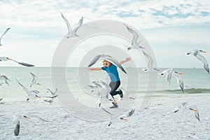 Kid playing in summer beach. Child run on the seagulls on the beach, summer time. Cute little boy chasing birds near sea