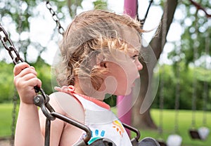 Kid playing on swing in summer