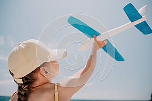 Kid playing with toy airplane. Children dream of travel by plane. Happy child girl has fun in summer vacation by sea and