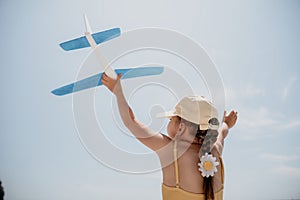 Kid playing with toy airplane. Children dream of travel by plane. Happy child girl has fun in summer vacation by sea and