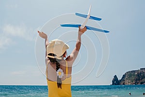 Kid playing with toy airplane. Children dream of travel by plane. Happy child girl has fun in summer vacation by sea and