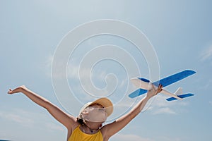 Kid playing with toy airplane. Children dream of travel by plane. Happy child girl has fun in summer vacation by sea and